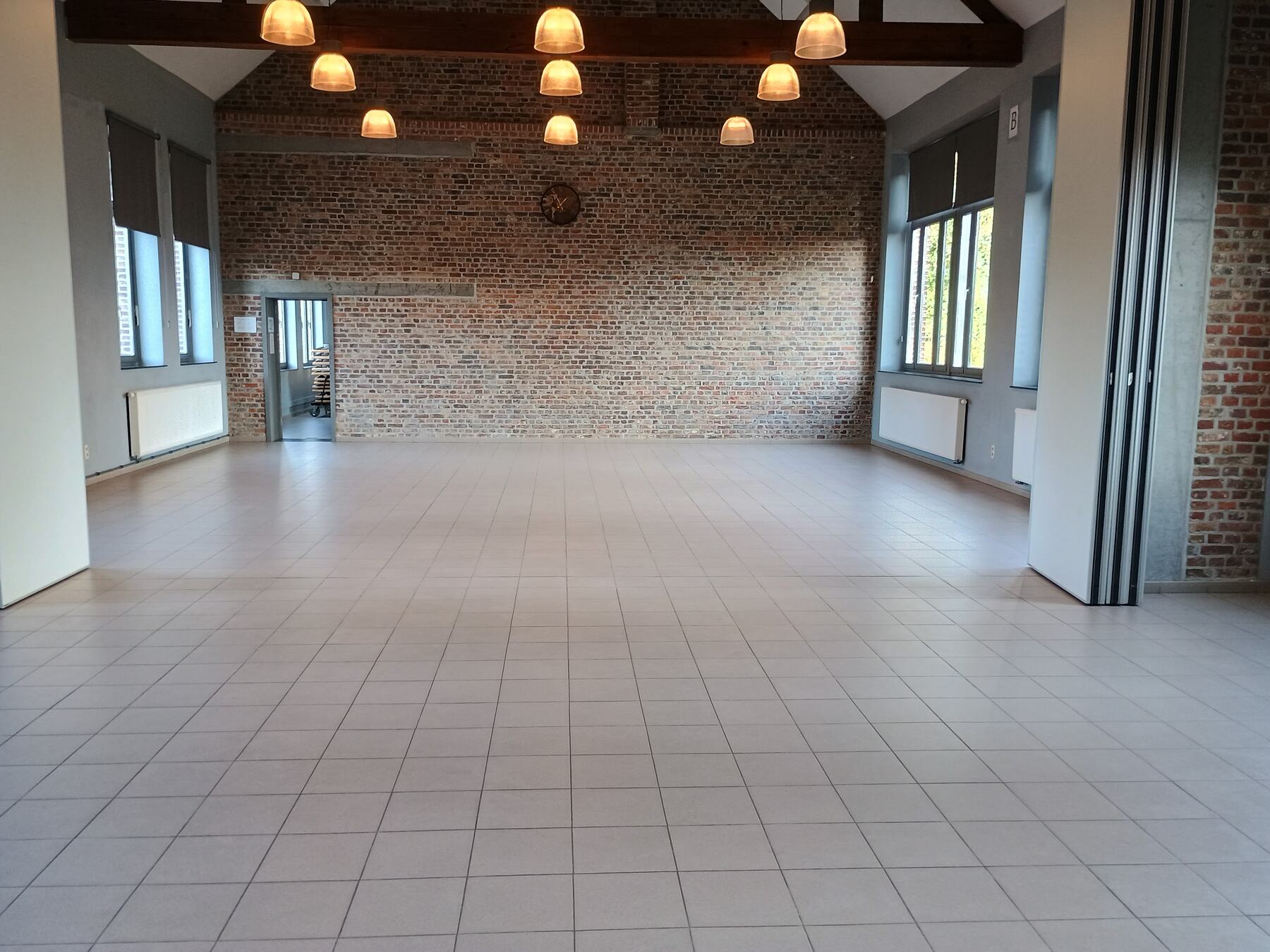 Zaal B met bakstenen muur en hanglampen
